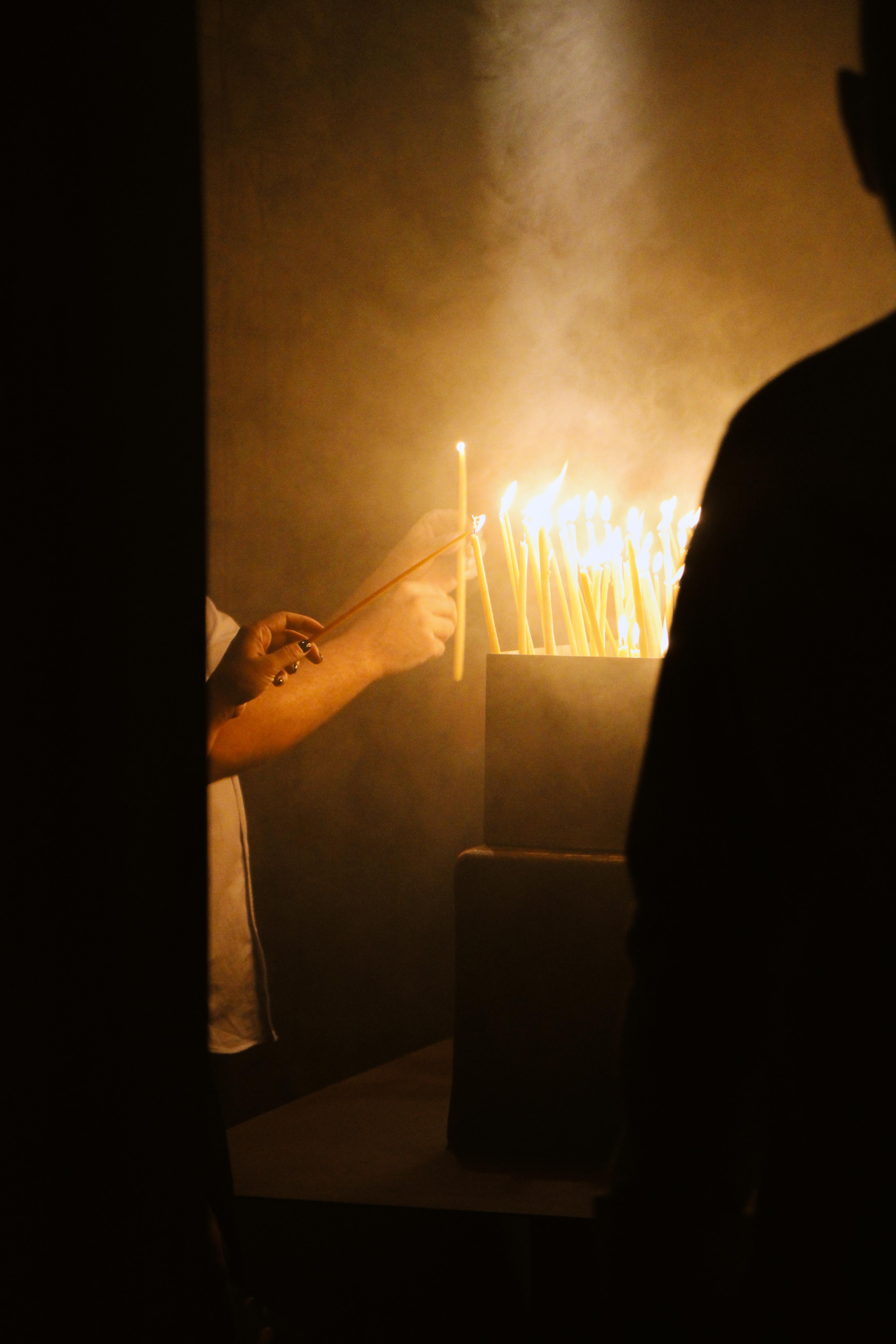 A man is seen lighting candles in a softly lit room, adding a touch of warmth and ambiance to the space.